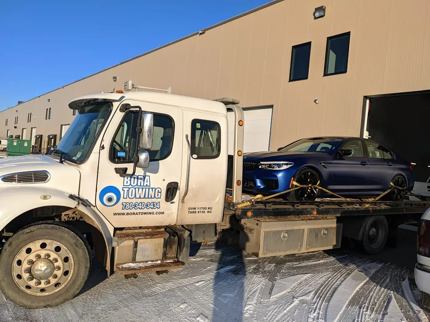Bora Towing flatbed transporting a blue BMW M5 in winter Edmonton