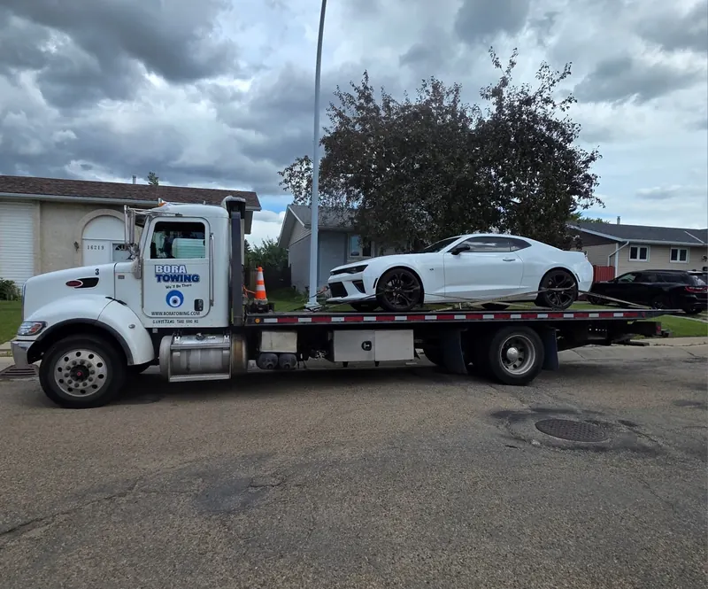 Bora Towing flatbed transporting white Chevrolet Camaro in Edmonton residential area