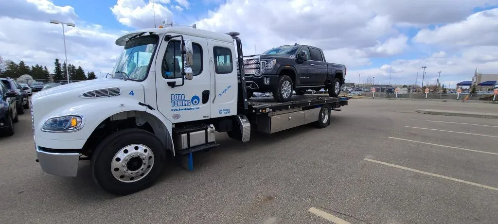 Bora Towing flatbed transporting a black GMC pickup truck in Edmonton