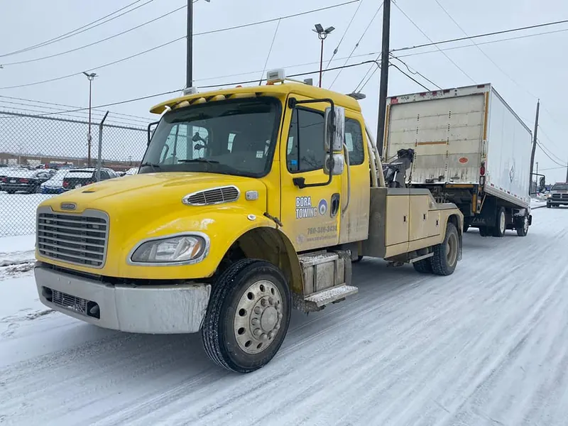 Bora Towing yellow wrecker towing semi-trailer in winter Edmonton